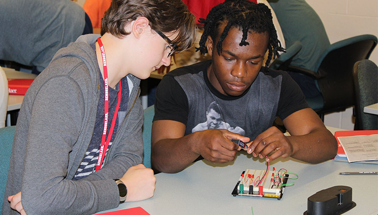 Engineering Ambassadors club member working with a student on a project.