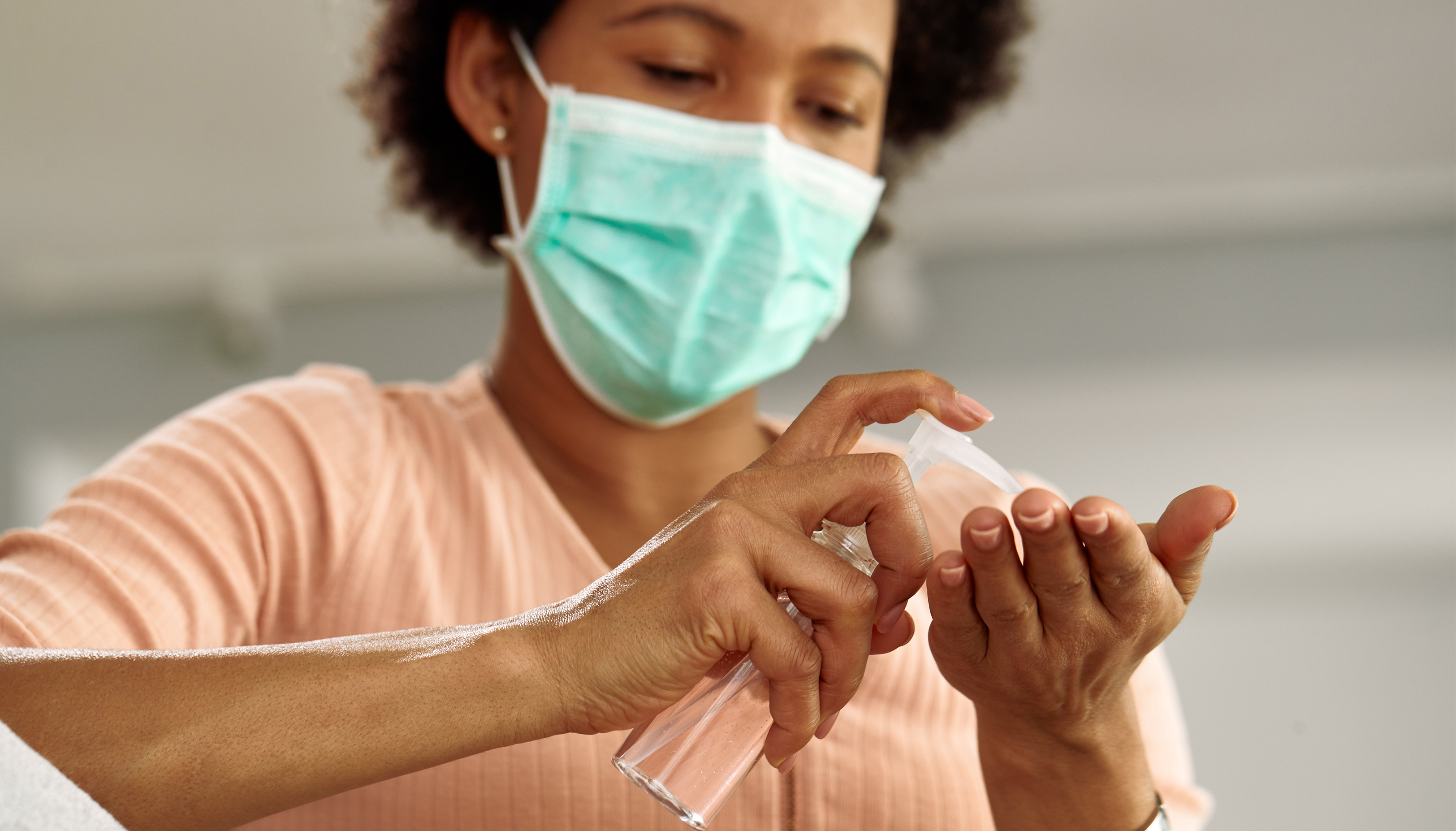 Woman wearing face mask using hand sanitizer
